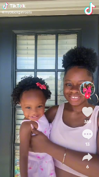 Young black mother, TriDereka Hall, holding small girl on her hip, both wearing pink and smiling