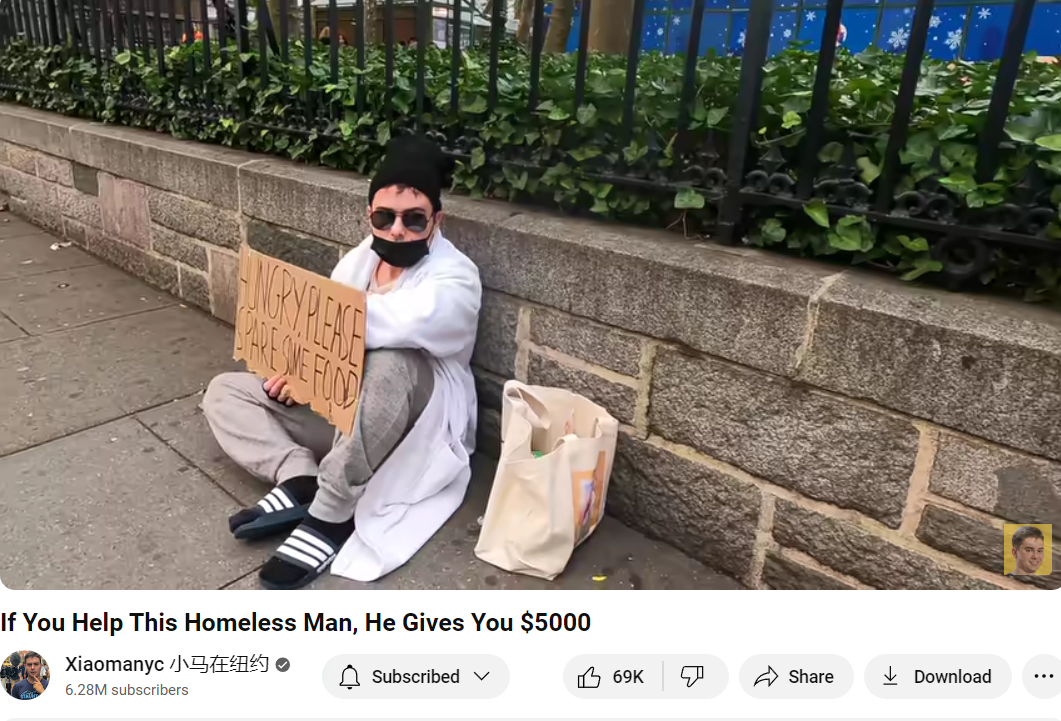 Young homeless man sitting beside park wall holding sign